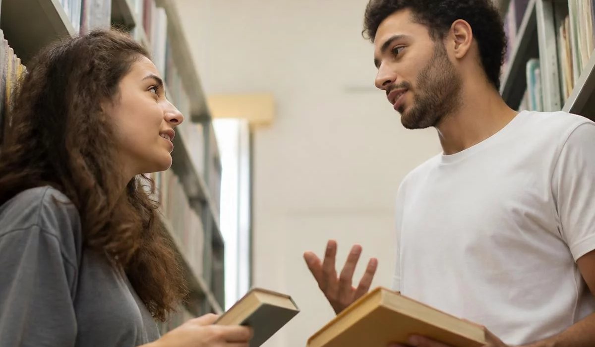 Pessoas conversando de pé junto às estantes antes de o encontro abrir